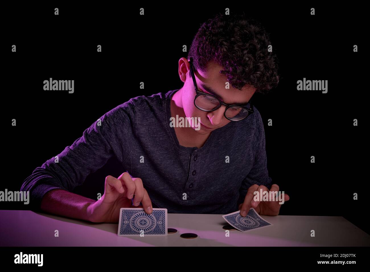 Junge Teenager kaukasischen Zauberer, tun einen Zaubertrick mit Karten auf einem Tisch mit Matte. Live-Performance. Stockfoto