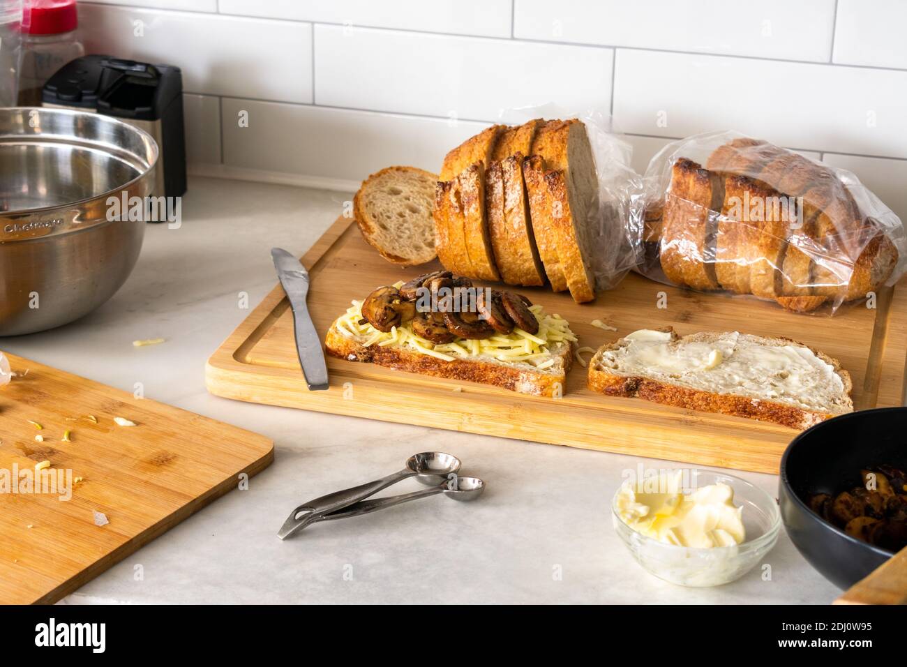 Zubereitung von Knoblauch Pilzbrötchen mit gegrilltem Käse: Ein gegrilltes Käse-Sandwich mit sautierten Pilzen zusammenstellen Stockfoto
