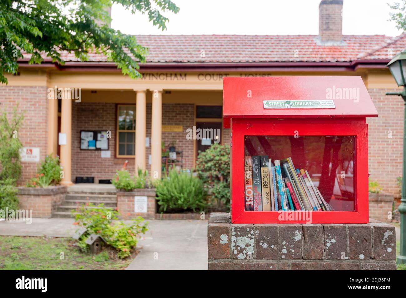 Eine Mini-Straßenbibliothek, die am Zaun vor dem Wingham Craft Center, dem ehemaligen Gerichtsgebäude im regionalen New South Wales, Australien, angebracht ist Stockfoto