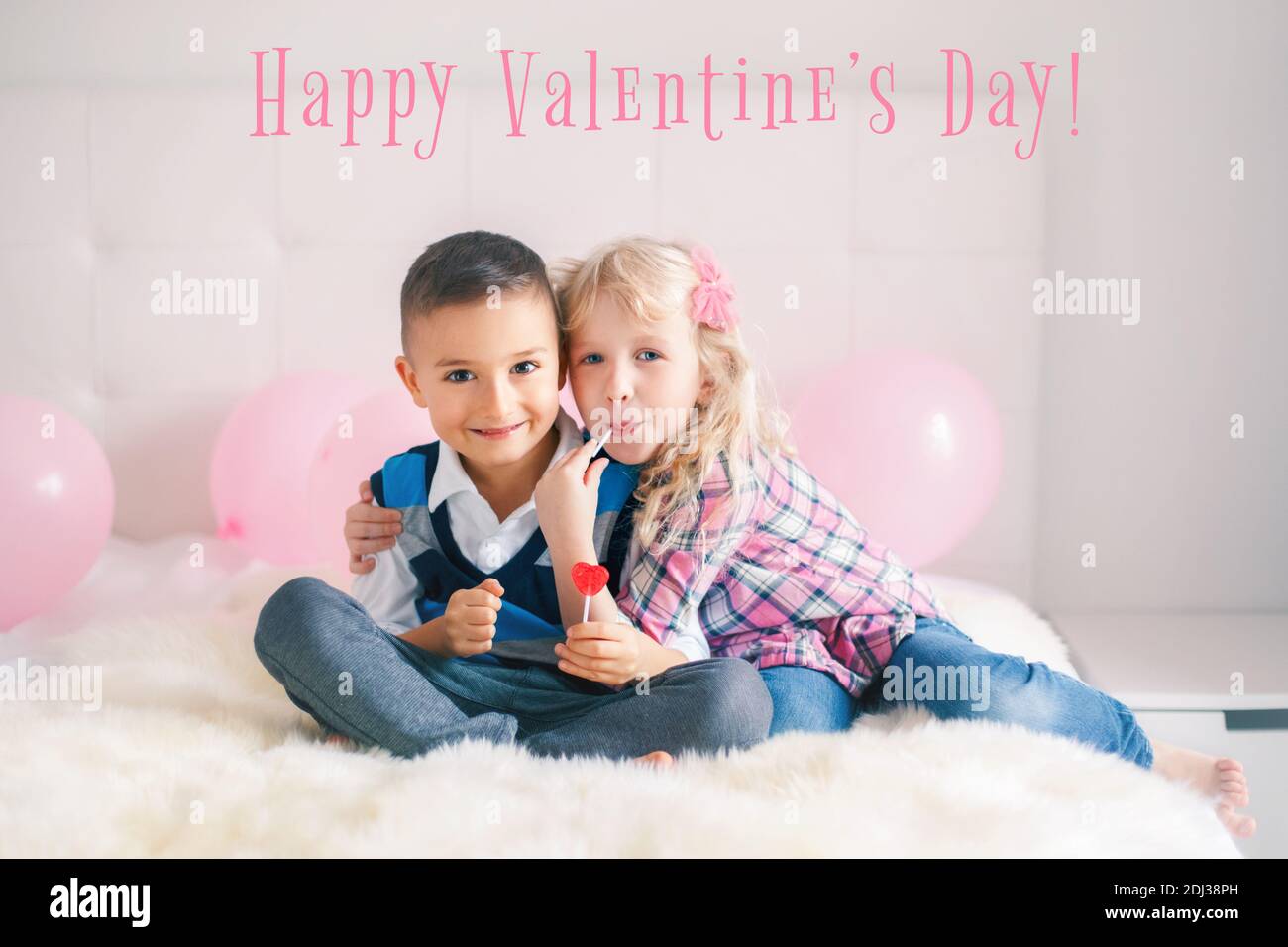 Alles Gute Zum Valentinstag. Weihnachtskarte mit Text. Zwei glückliche kaukasische Kinder essen herzförmige Lutscher. Junge und Mädchen feiern Valentinstag. Liebe Stockfoto