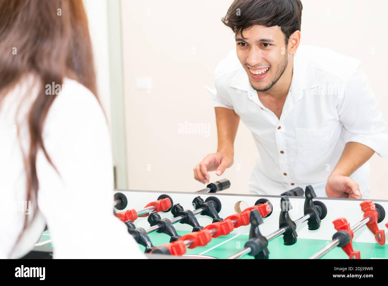 Glückliche junge Mann spielt Tischkicker Fußball mit Freundin. Paar Freizeit und Lifestyle. Stockfoto