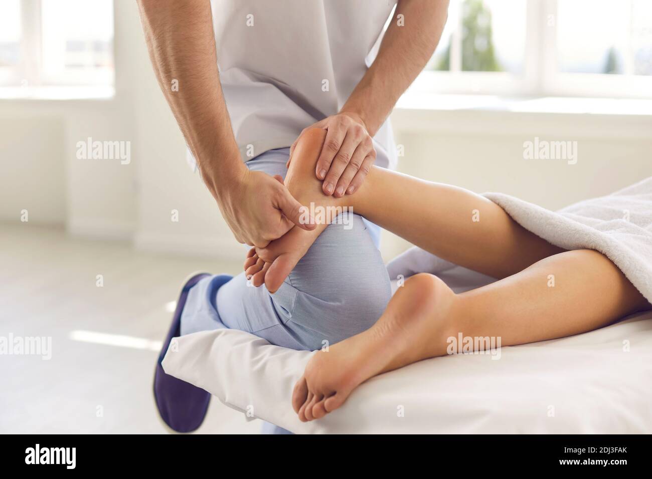 Zugeschnittenes Bild der Hand eines orthopädischen Arztes, der den Fuß eines Patienten untersucht und massiert. Stockfoto