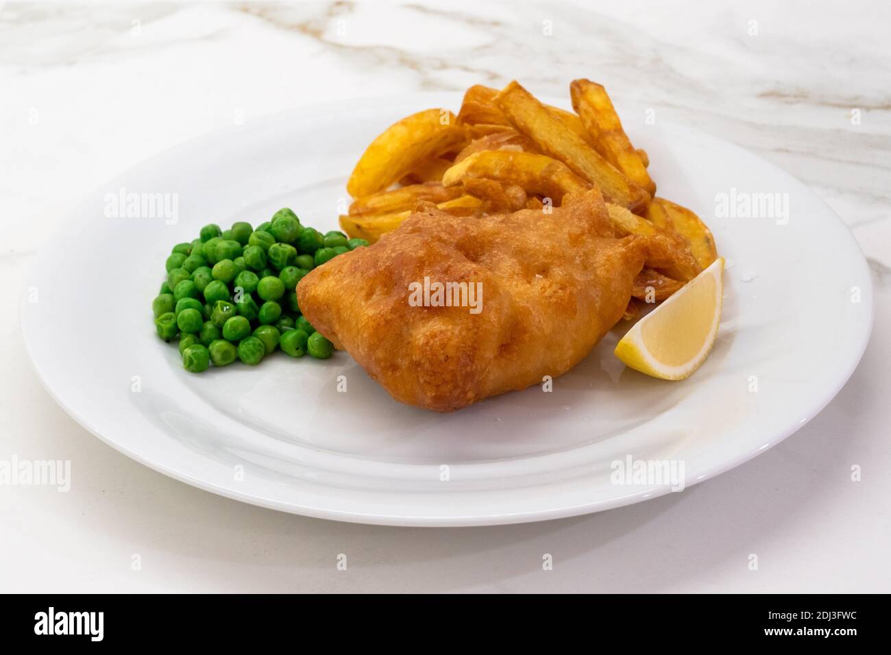 Fisch und Chips mit Erbsen und Zitrone auf einem weißen Teller, ein typisches traditionelles Gericht der britischen Küche mit tiefgebratenen Kabeljau Stockfoto