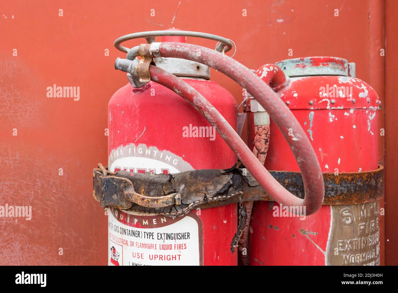 Zwei alte und verfallene Feuerlöscher an der Seite montiert Eines alten Feuerwehrwagens in Australien Stockfoto