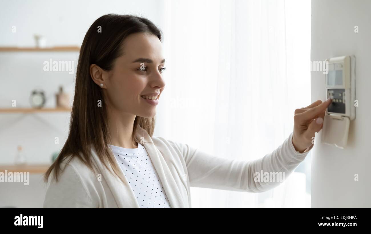 Lächelnde junge Frau drückt Tasten auf Smart House-System Stockfoto