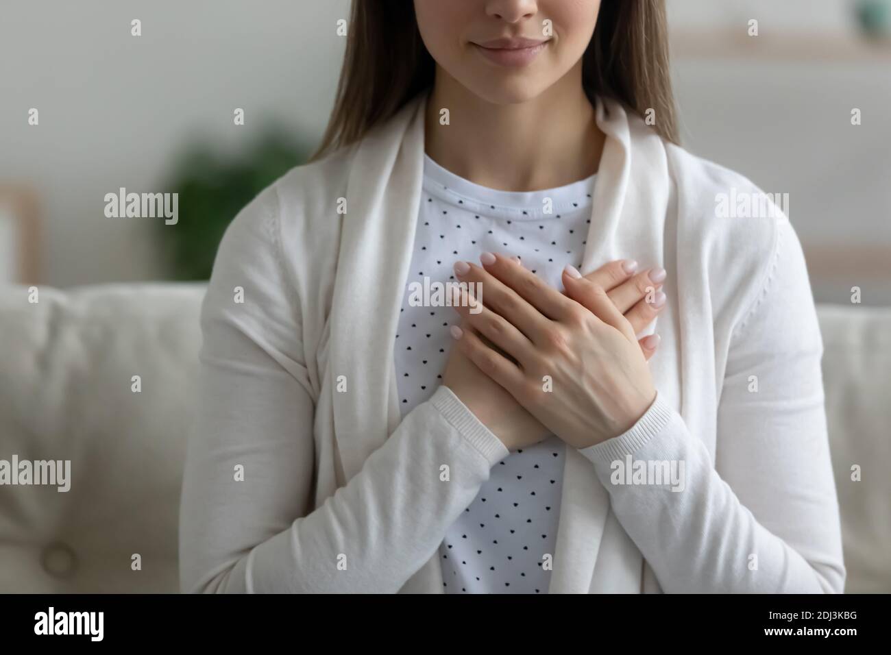 Nahaufnahme Wunschhafte friedliche junge Frau, die die Hände auf der Brust hält Stockfoto