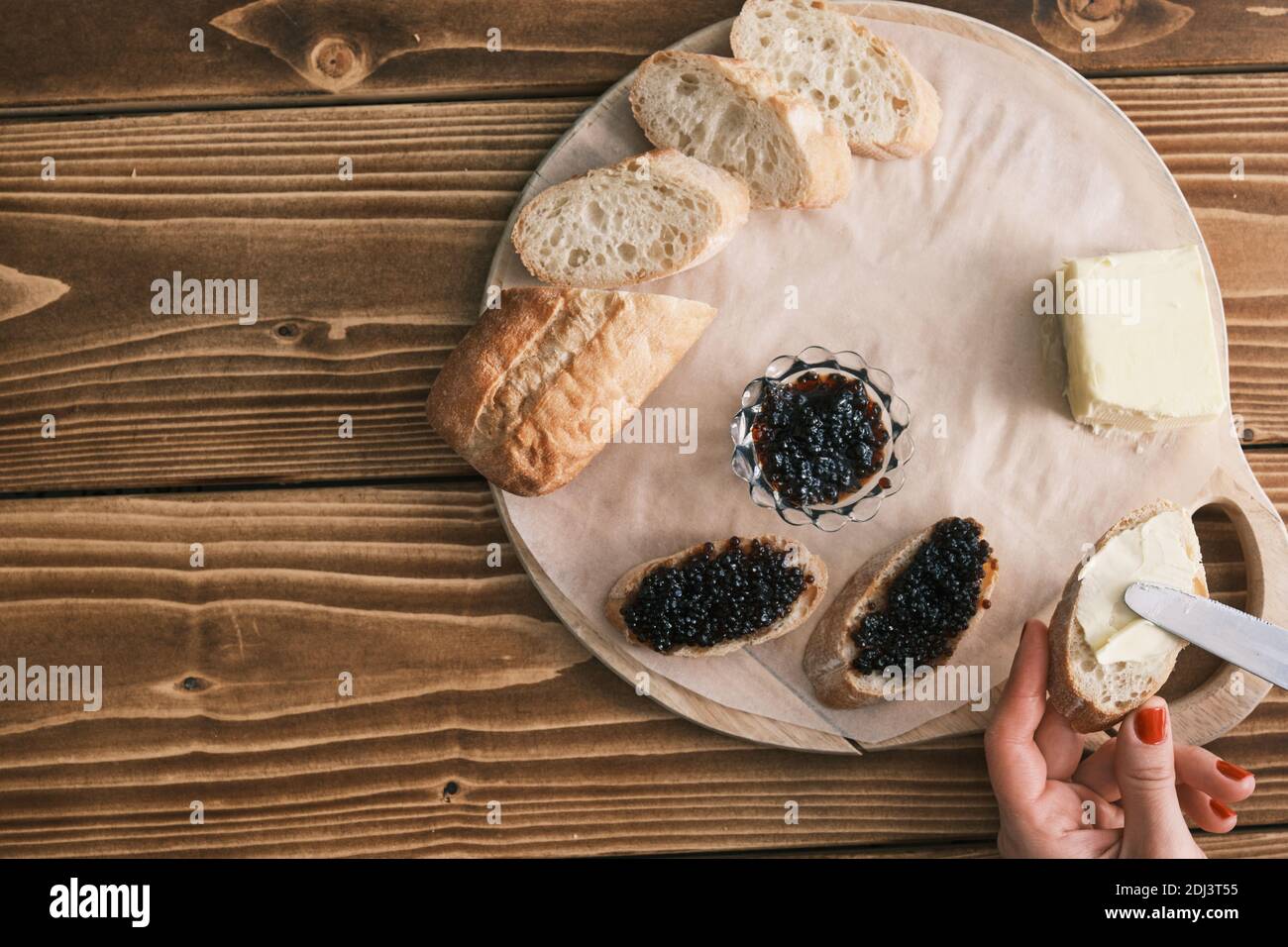 Stör schwarzer Kaviar auf einem Holzbrett mit Butter Stockfoto