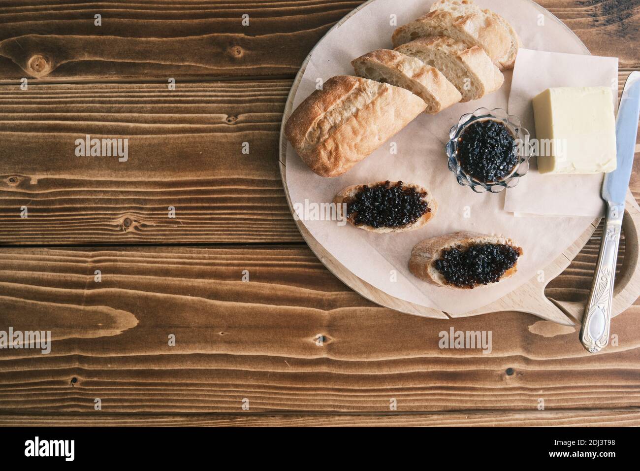 Stör schwarzer Kaviar auf einem Holzbrett mit Butter Stockfoto