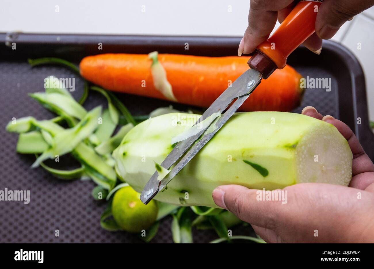 Gurkenschälchen als Teil der Vorbereitung für das spätere Kochen Stockfoto