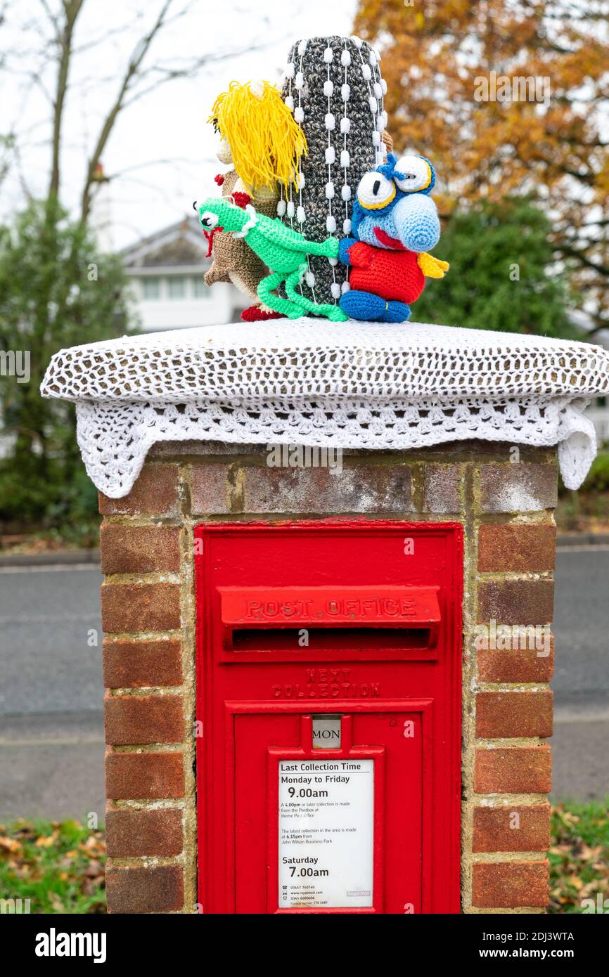 Britische traditionelle rote Briefkästen mit Strickmützen als Weihnachtsdekoration. Muppet Figuren aus der berühmten TV-Show. Stockfoto