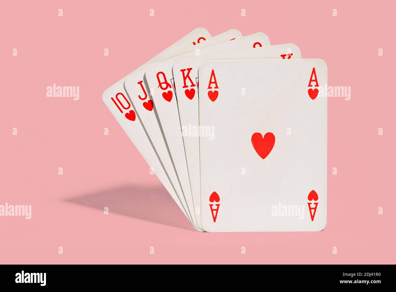 Gewinnende Hand der Spielkarten im Poker zeigt eine königliche Flush oder Straight Flush im Anzug der Herzen ass Durch zehn auf rosa Hintergrund mit Schatten Stockfoto