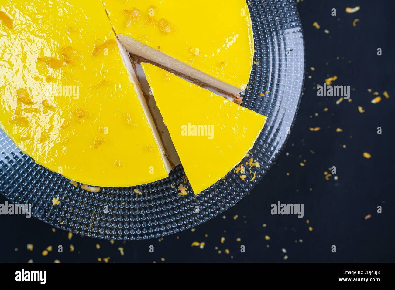 Geschnitten ​​lemon Käsekuchen auf Glasplatte auf schwarzem Hintergrund. Stockfoto