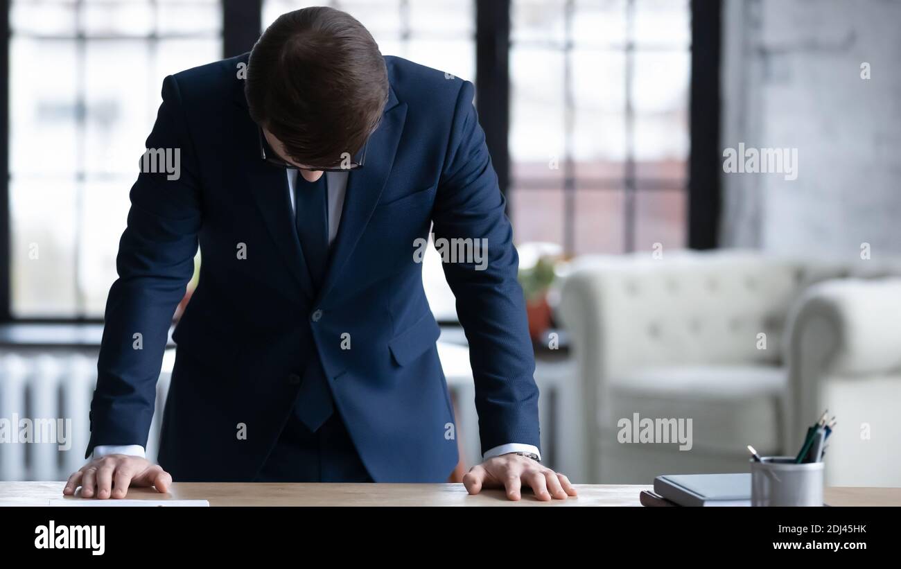 Nahaufnahme frustrierter Geschäftsmann, der mit dem Kopf nach unten am Schreibtisch steht Stockfoto