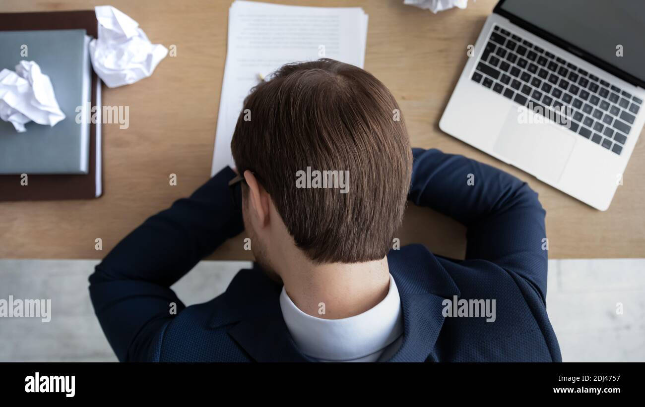 Draufsicht überarbeiteter müder Geschäftsmann, der Anzug trägt und am Arbeitsplatz schläft Stockfoto