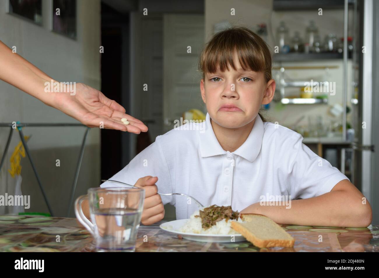 Das Mädchen mag die von ihr angebotenen Medikamente nicht Mutter vor dem Abendessen Stockfoto