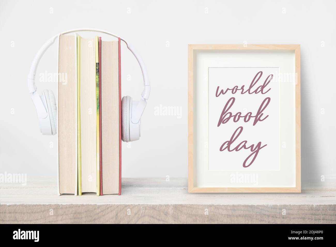 Bücher und Kopfhörer neben einem Holzrahmen mit dem Text World Book Day. Stockfoto