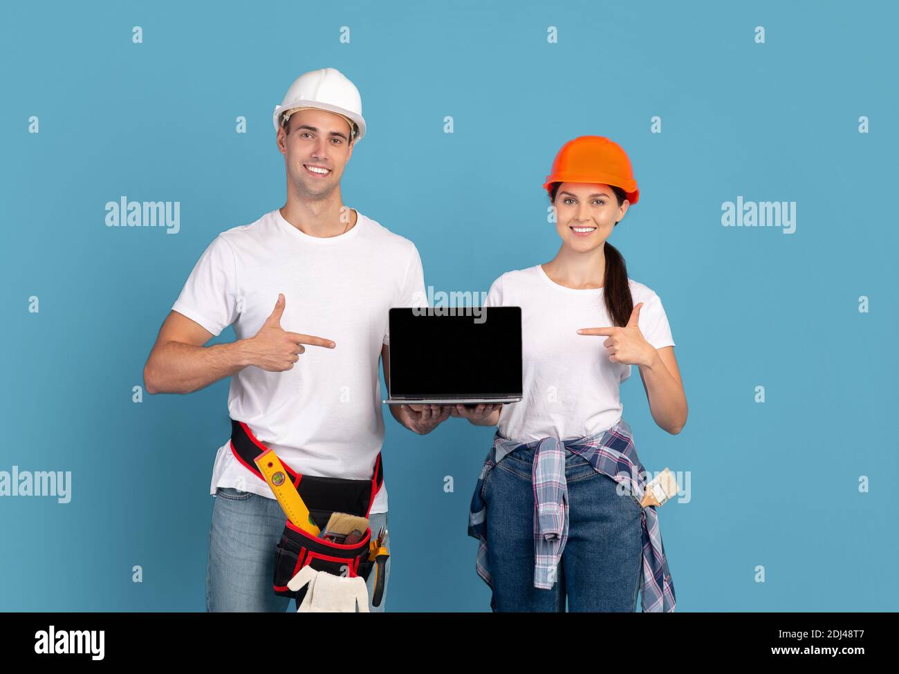 Home Repair Website. Paar In Hard Hats Holding Laptop Mit Schwarzem Bildschirm Stockfoto