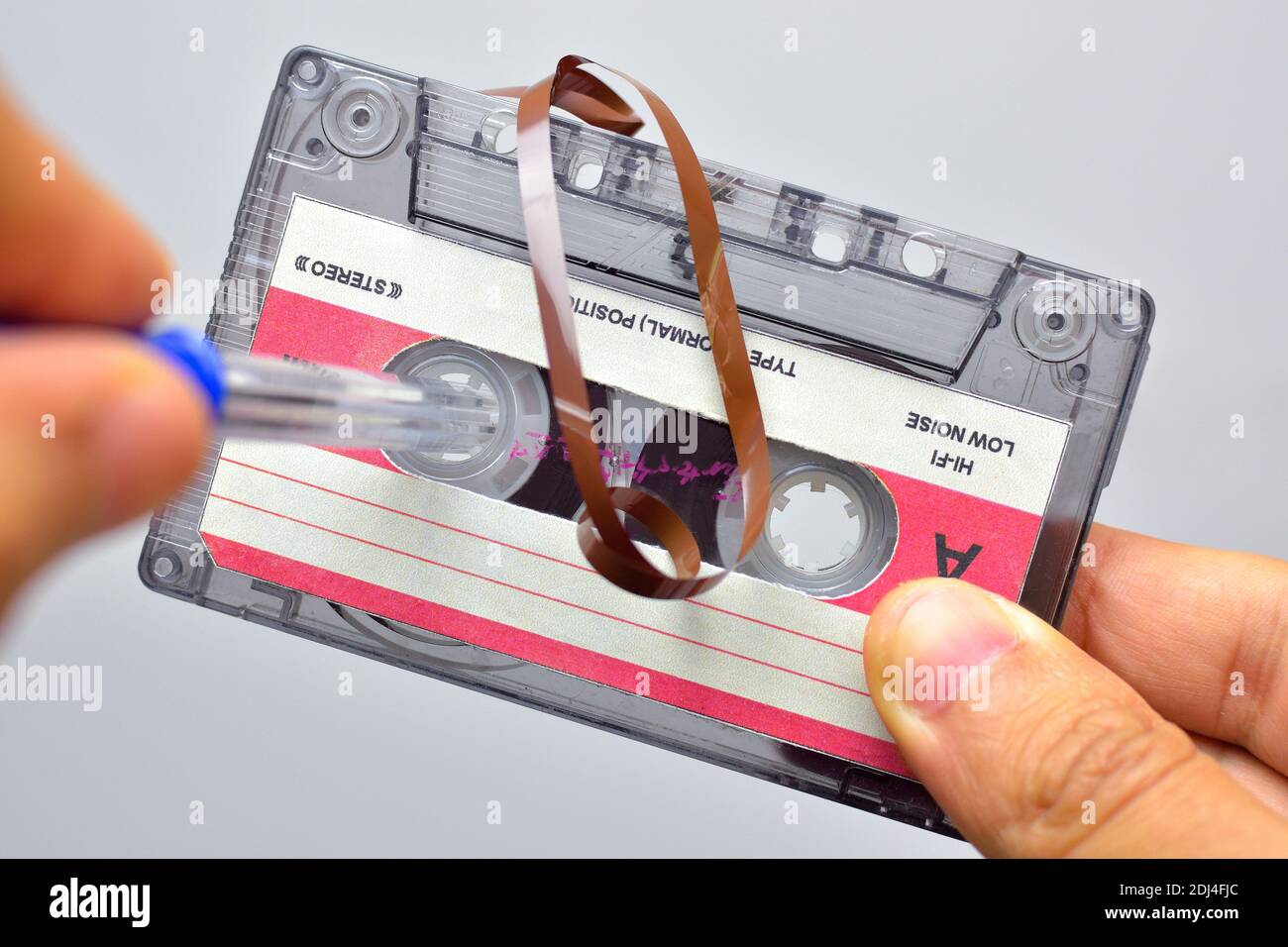 Halten einer alten Audiokassette, um das Magnetband auszurichten Mit Stift Stockfoto