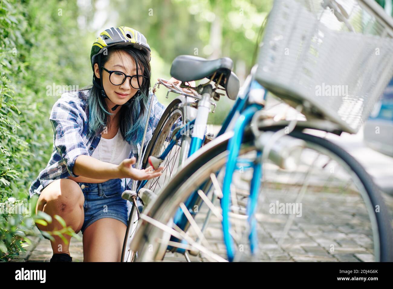 Frau, die auf gebrochene Fahrradkette schaut Stockfoto