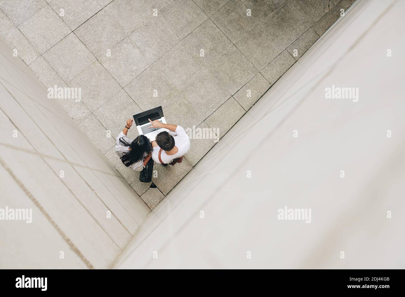 Geschäftskollegen stehen in der Zimmerecke und diskutieren Informationen auf dem Laptop-Bildschirm, Blick von oben Stockfoto