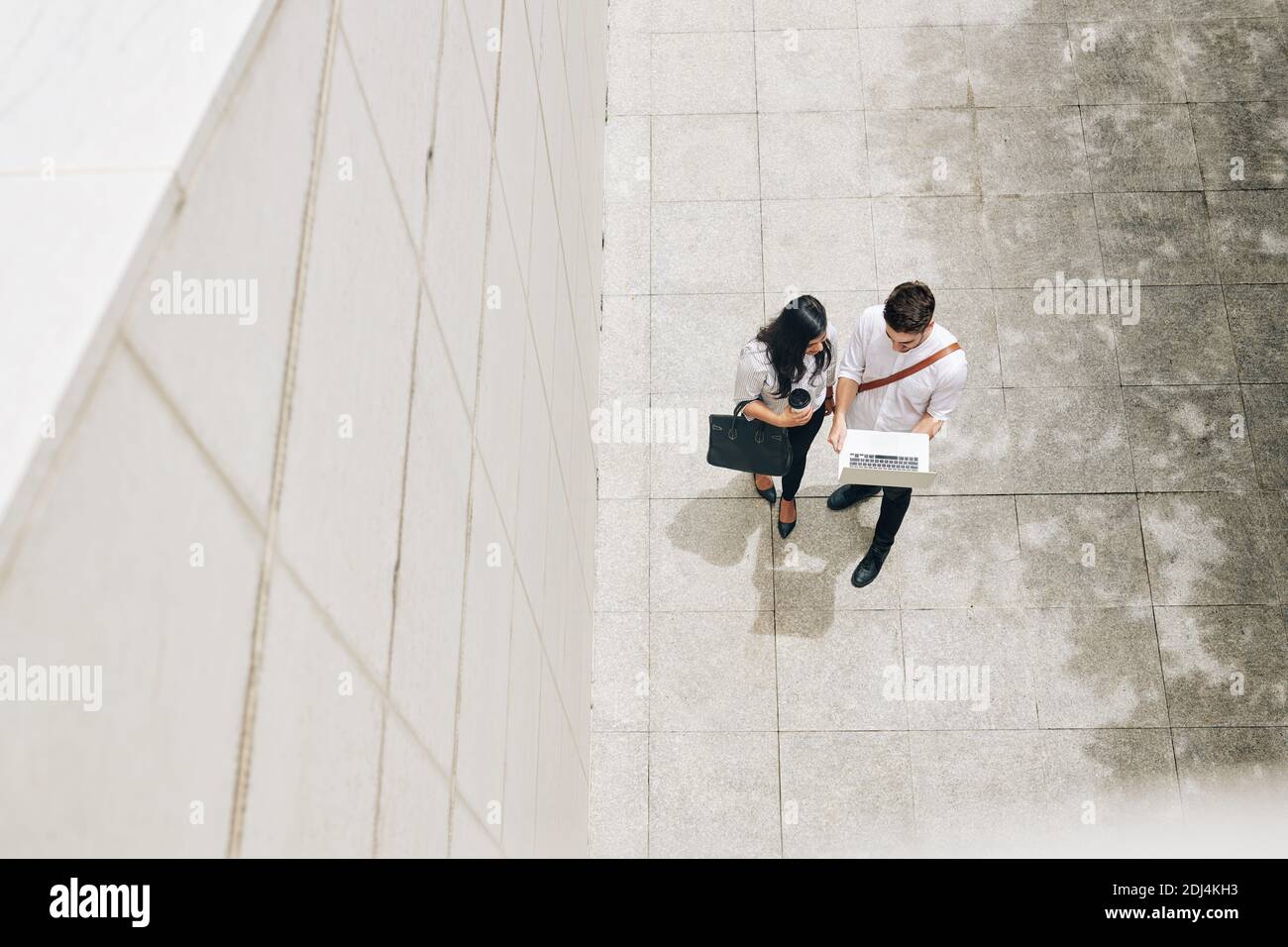 Stolzer junger Mann, der ein Projekt zeigt, an dem er arbeitete Kollegen, wenn sie durch das Bürogebäude gehen Stockfoto