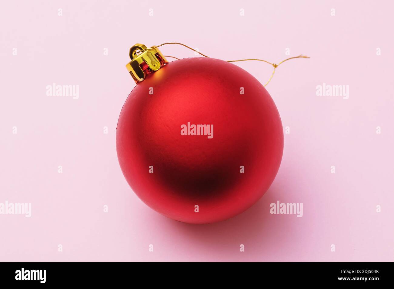 Rotes Christbaumspielzeug in Form einer Kugel auf einem rosa Hintergrund, Draufsicht. Stockfoto