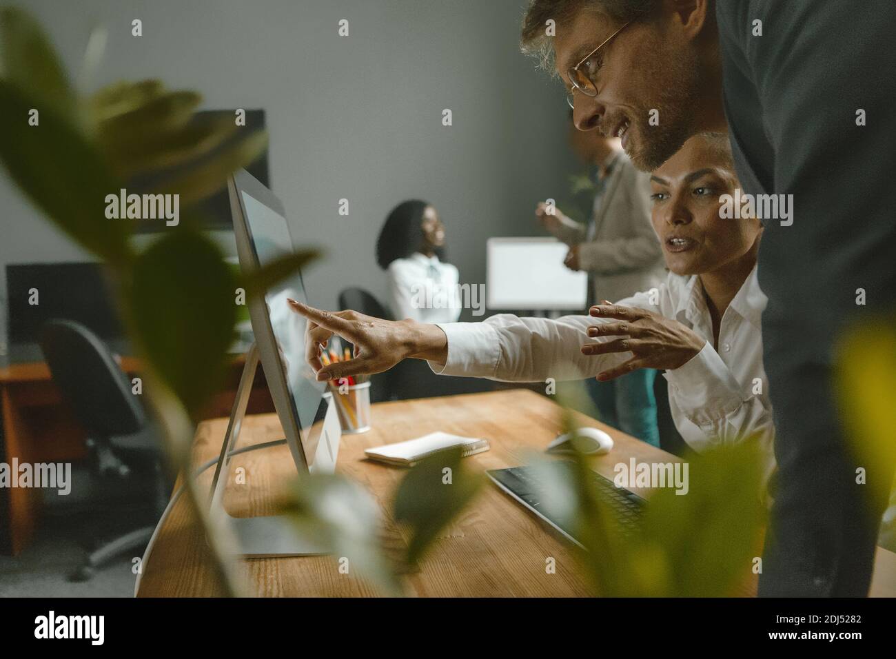 Coworking Team mit Mädchen zeigt ihrem Vorgesetzten neue Einstellungen. Die Mitarbeiter arbeiten im Team hart an der Umsetzung des Projekts. Teamwork-Konzept Stockfoto