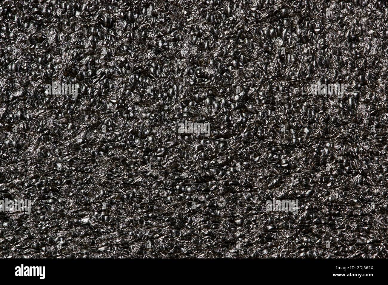 Schwarzer geschäumter Polyethylenschaum-Probenhintergrund. EPE Perlen Verpackungsmaterial mit Makro-Details, Texturen und einer einfarbigen Farbe. Stockfoto