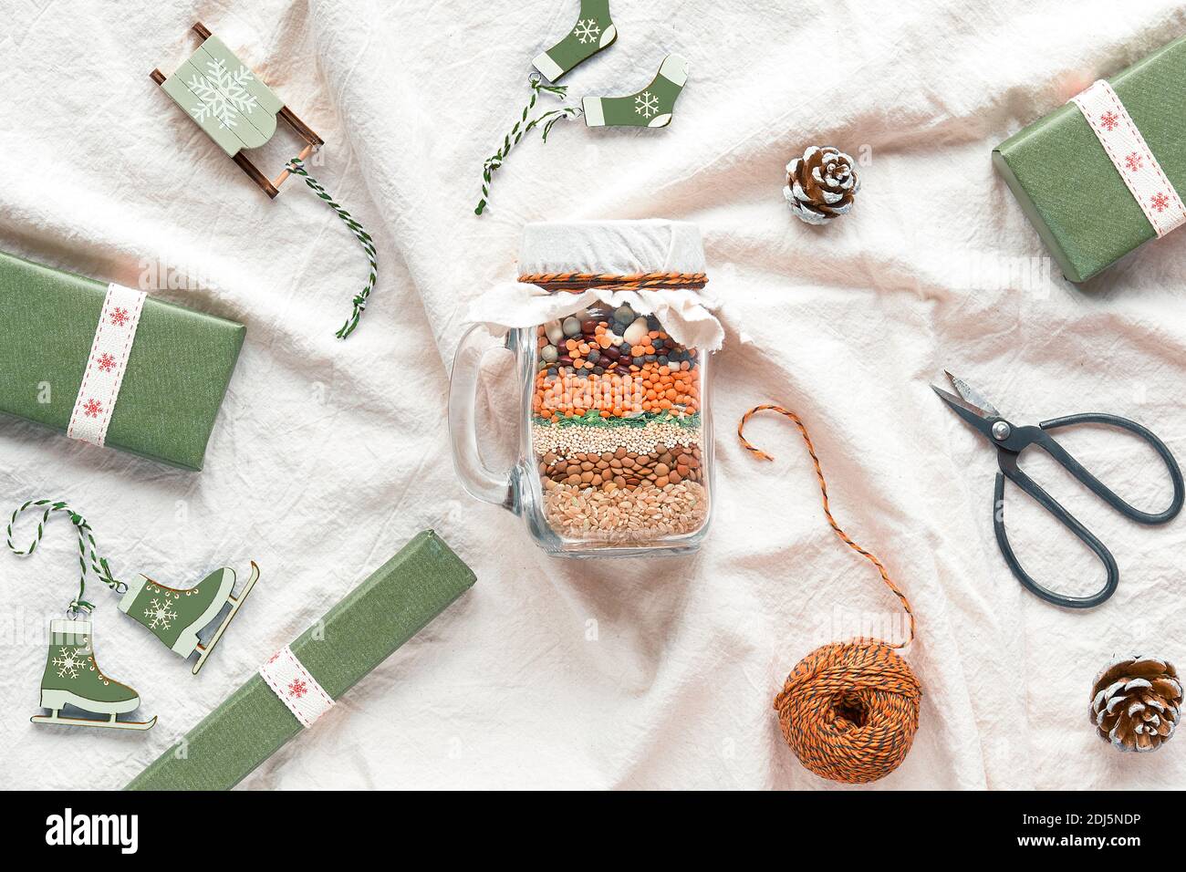 Zero Waste Weihnachtsgeschenk in einem Glas. Geschichtete Bohnenmischung mit Gewürzen auf weichem weißen Textil-Hintergrund ohne Kunststoff Holz Winter Xmas Dekorationen Stockfoto