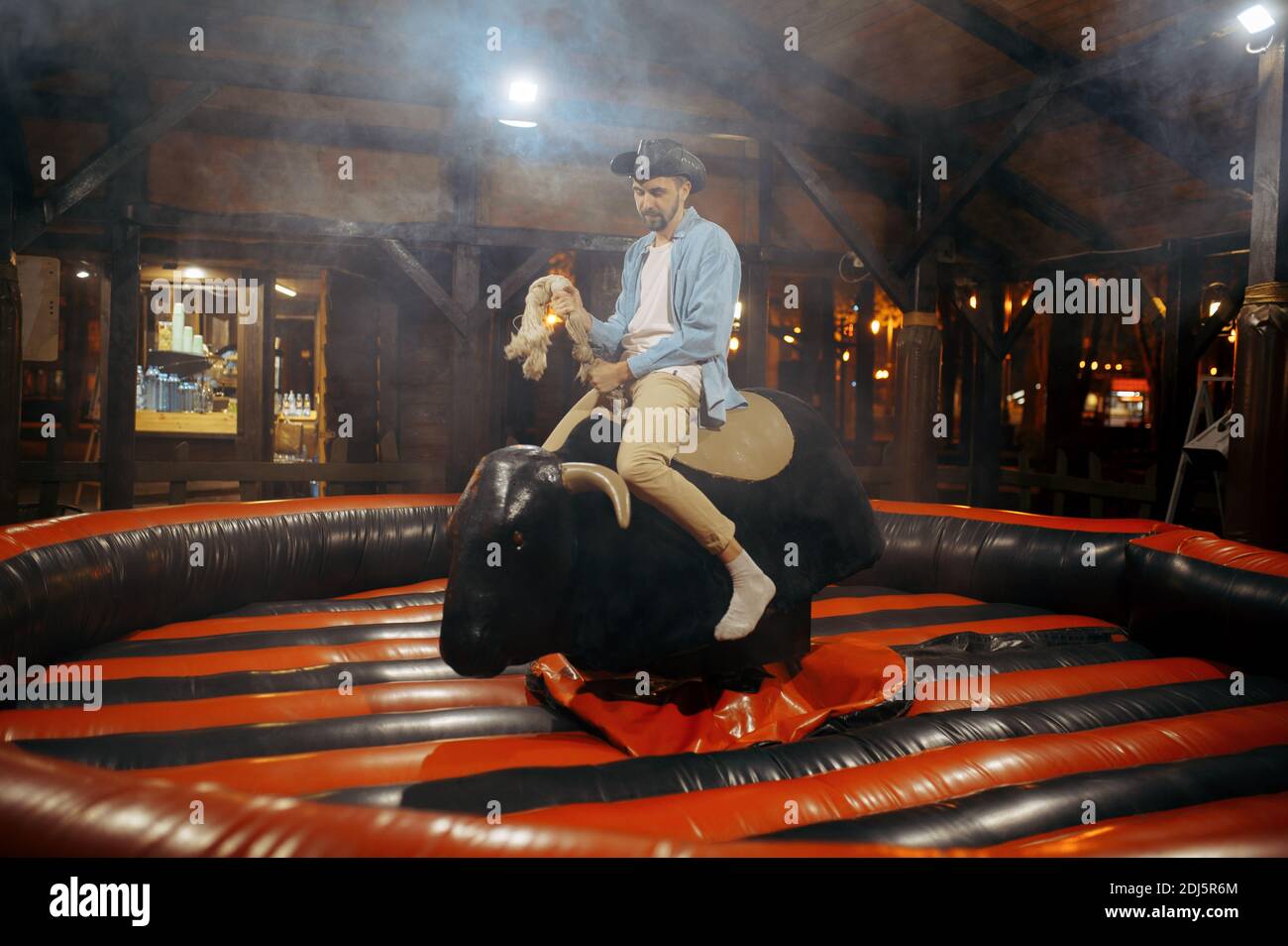 Mann auf Rodeo Attraktion im Nachtvergnügungspark Stockfoto