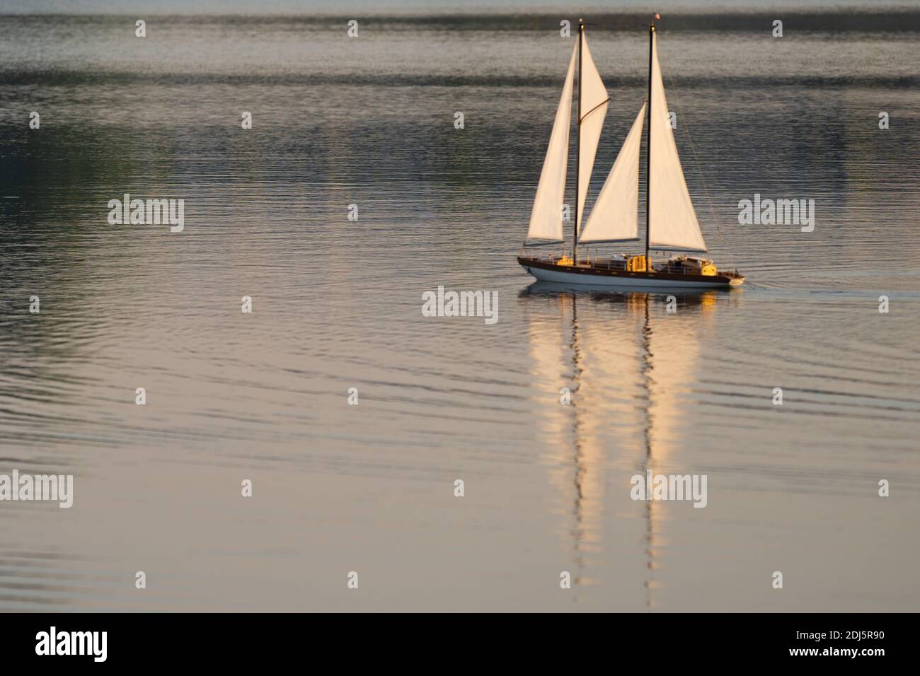 Miniatur-Segelboot auf einem ruhigen See im Morgenlicht. Stockfoto