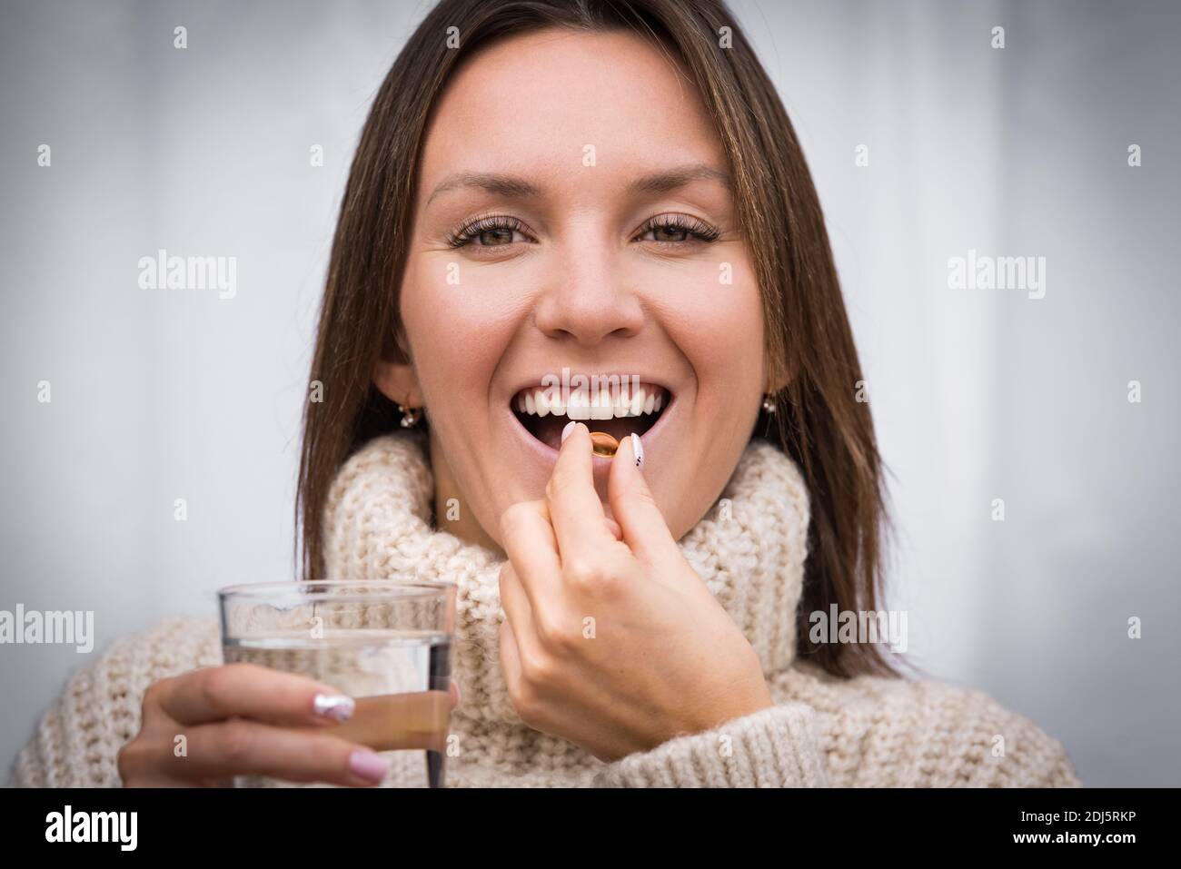 Junge schöne lächelnde Frau nimmt Fischöl Pille. Einnahme der Kapsel mit Omega 3 oder Vitamin D3. Vitamin-D-Ergänzungen Stockfoto