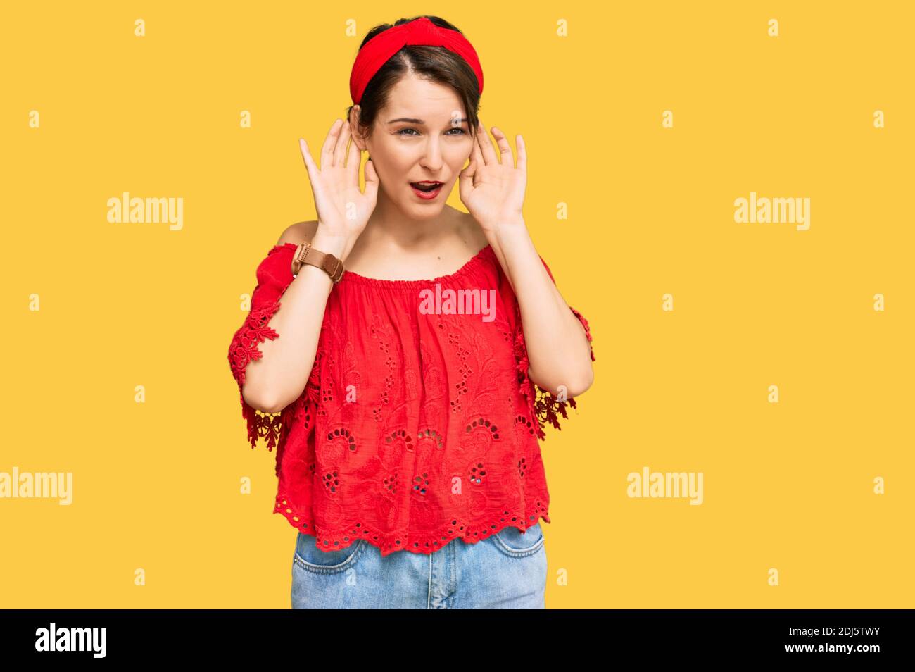 Junge Brünette Frau mit kurzen Haaren tragen lässige Sommerkleidung und Diadem versuchen, beide Hände auf Ohr Geste hören, neugierig auf Klatsch. Hörpr Stockfoto