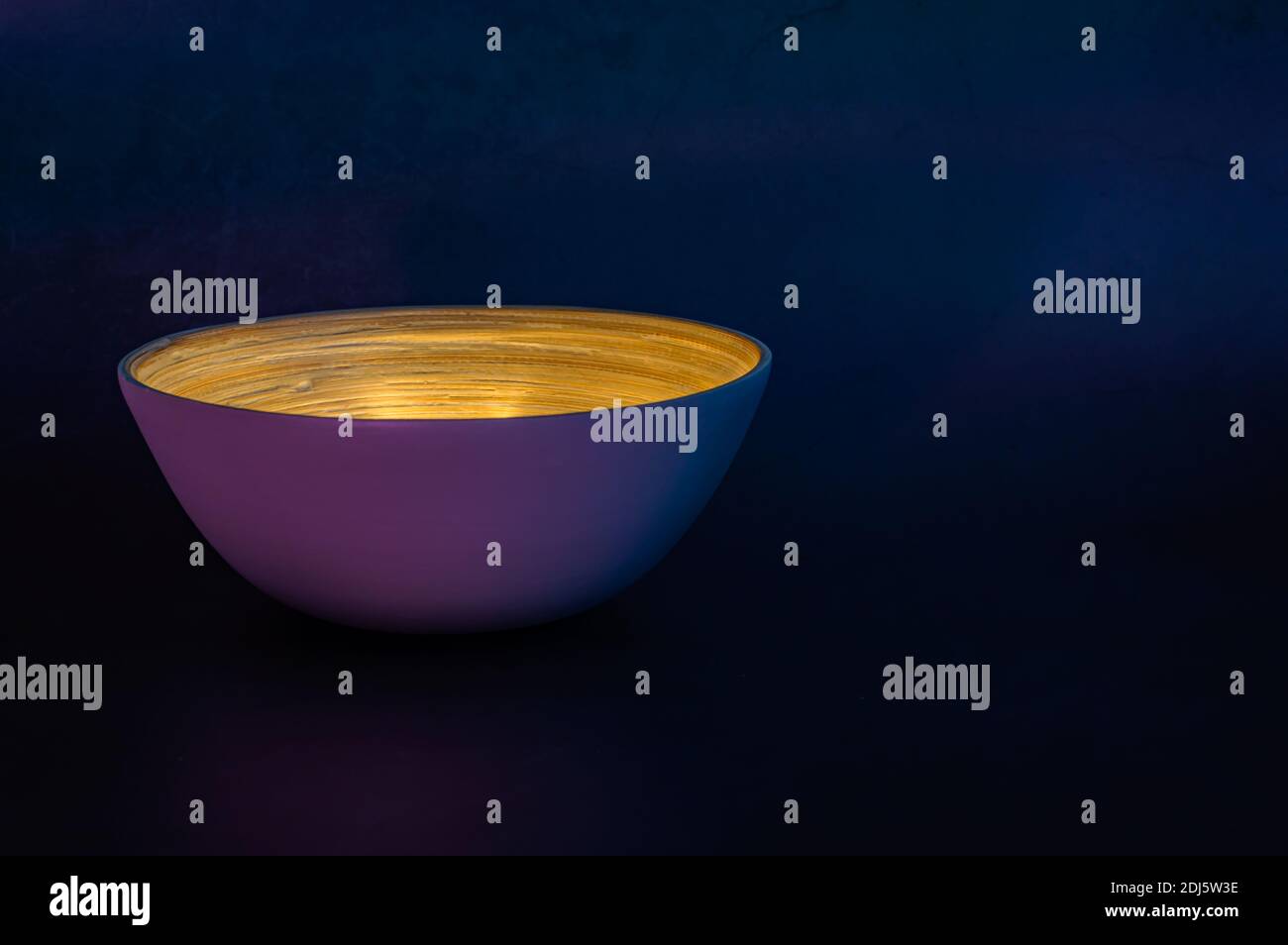 Bild einer Bambusschüssel gefüllt mit Licht in einem Dunkle Umgebung mit blauen und violetten Tönen Stockfoto