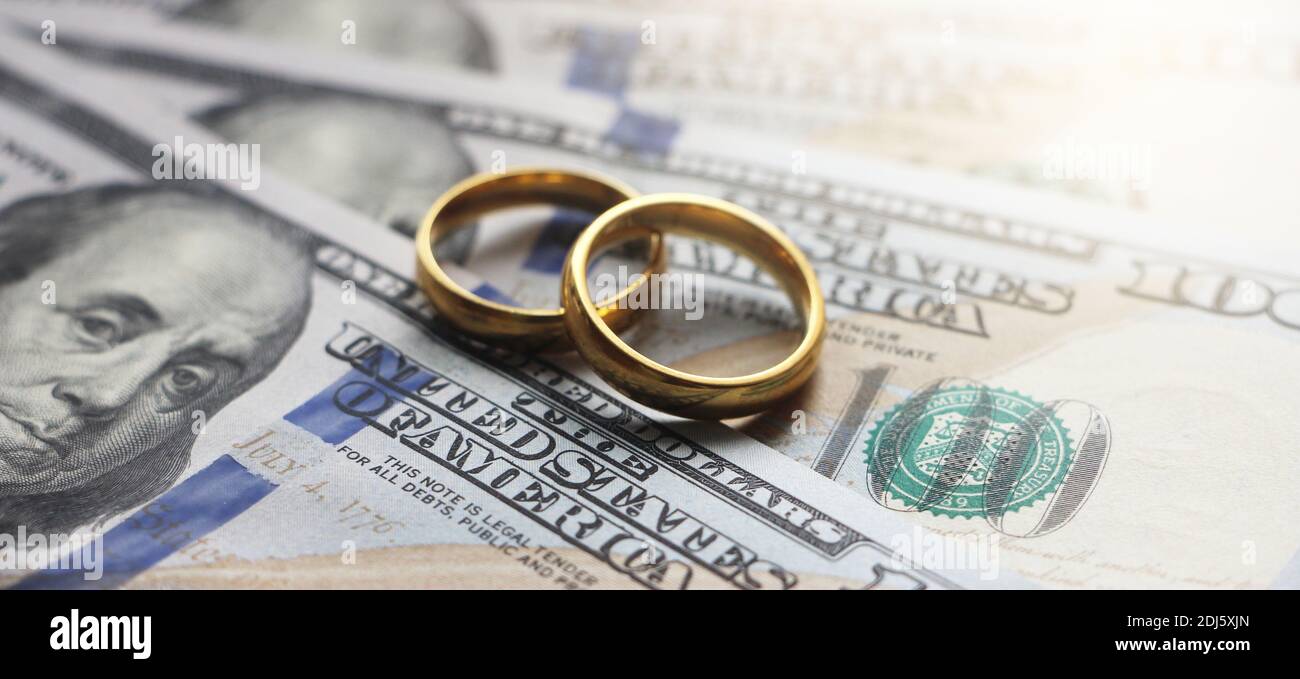 Eheringe auf dem Hintergrund von 100 Dollar Scheine. Ehe contract oder prenuptial Vereinbarung Konzept Stockfoto