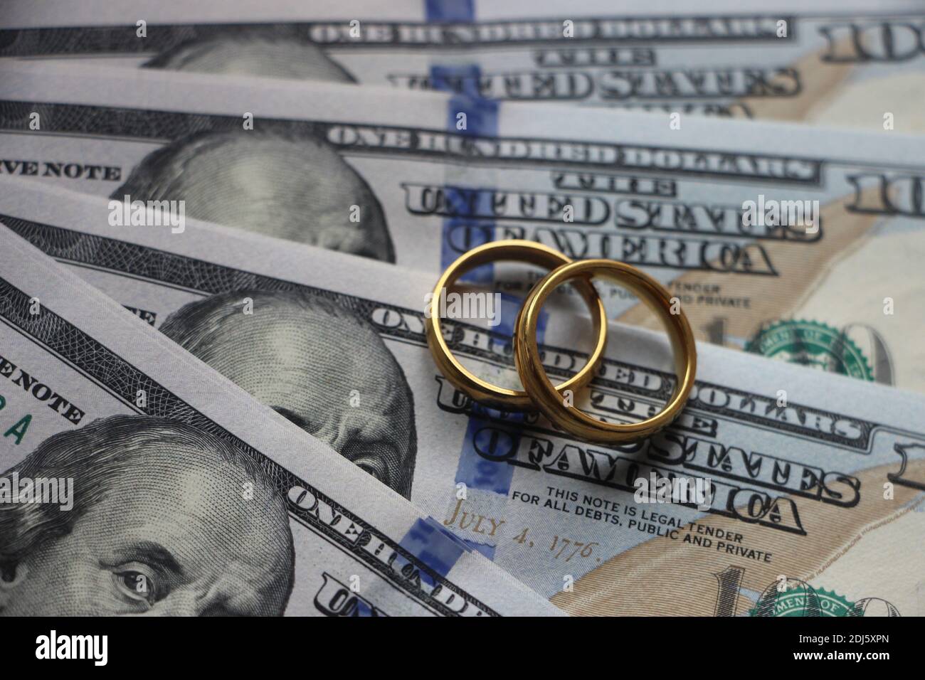 Eheringe auf dem Hintergrund von 100 Dollar Scheine. Ehe contract oder prenuptial Vereinbarung Konzept Stockfoto