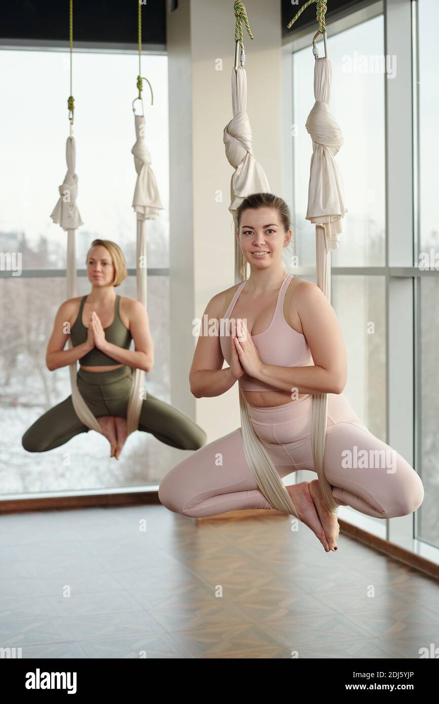 Zwei junge, energische Frauen in Sportkleidung halten das Gleichgewicht während des Sitzens In Fliege Yogamatten mit ihren Händen und Füßen setzen Gemeinsam Stockfoto