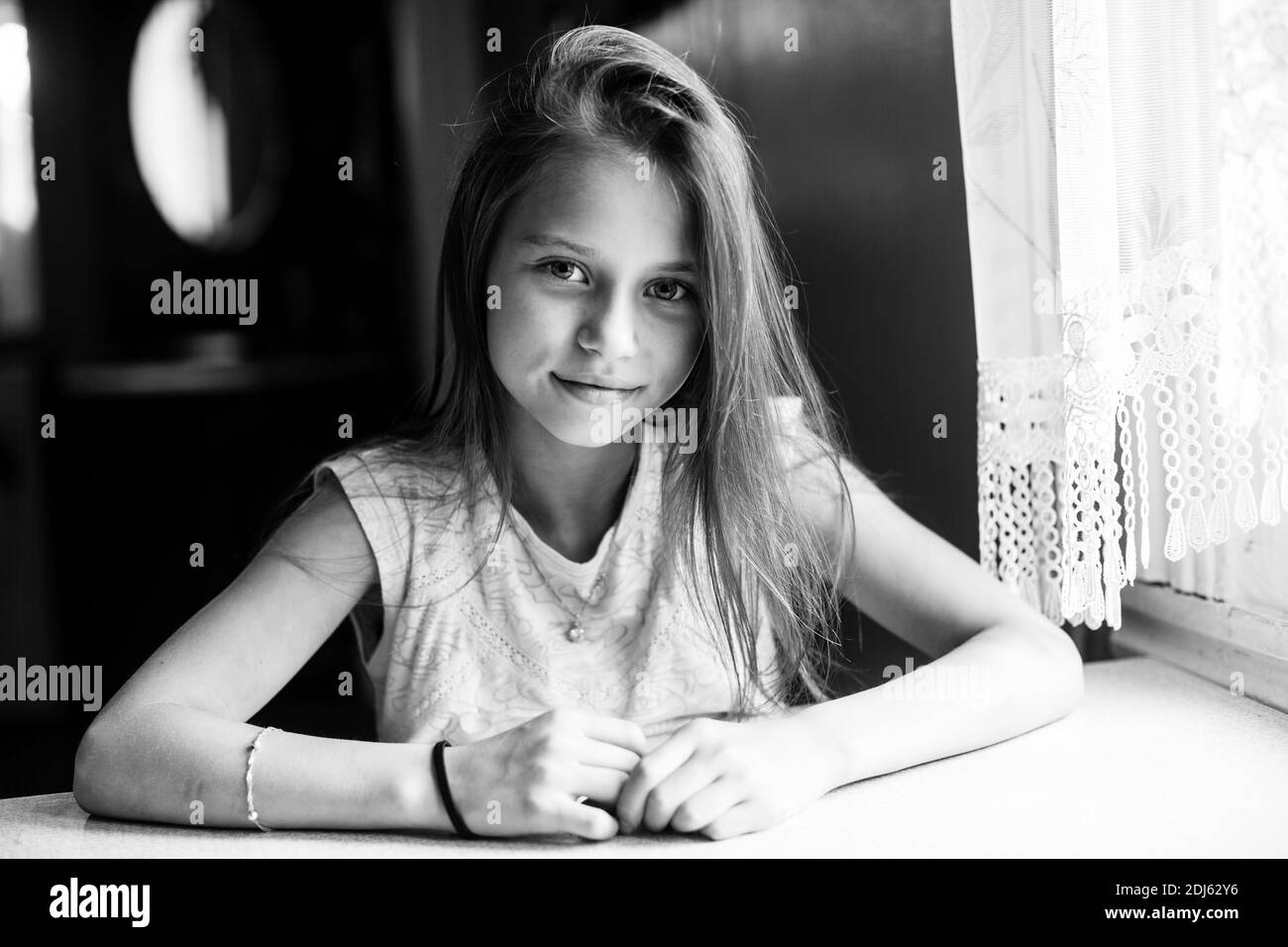 Mädchen sitzt am Tisch. Schwarzweiß-Fotografie. Stockfoto
