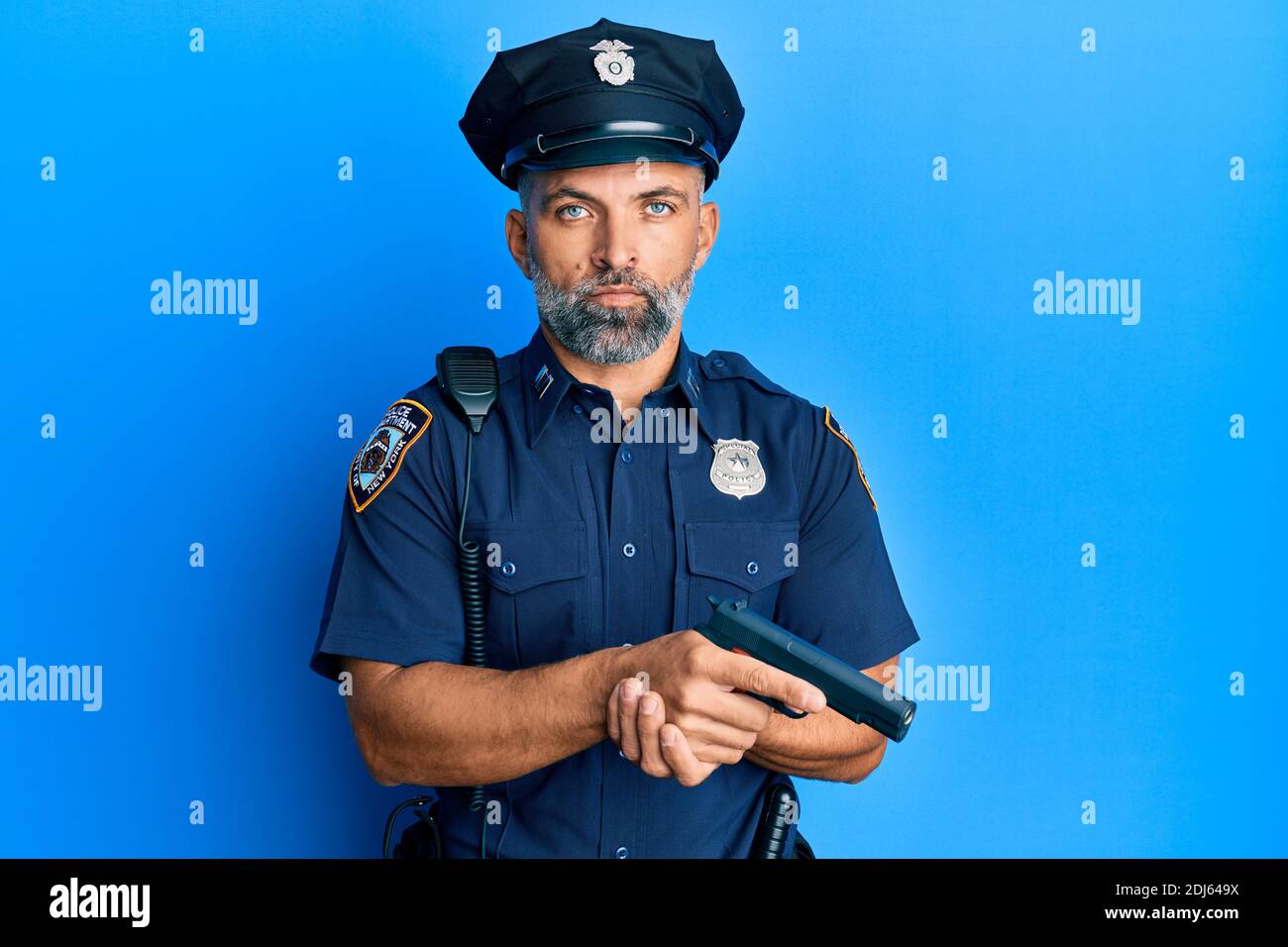 Mittelalter schöner Mann trägt Polizei Uniform halten Waffe entspannt mit ernsten Ausdruck auf Gesicht. Einfach und natürlich Blick auf die Kamera. Stockfoto