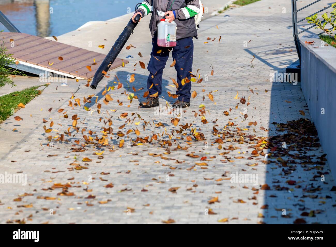 Außenarbeiter bläst gefallene Blätter in den Park. Stockfoto