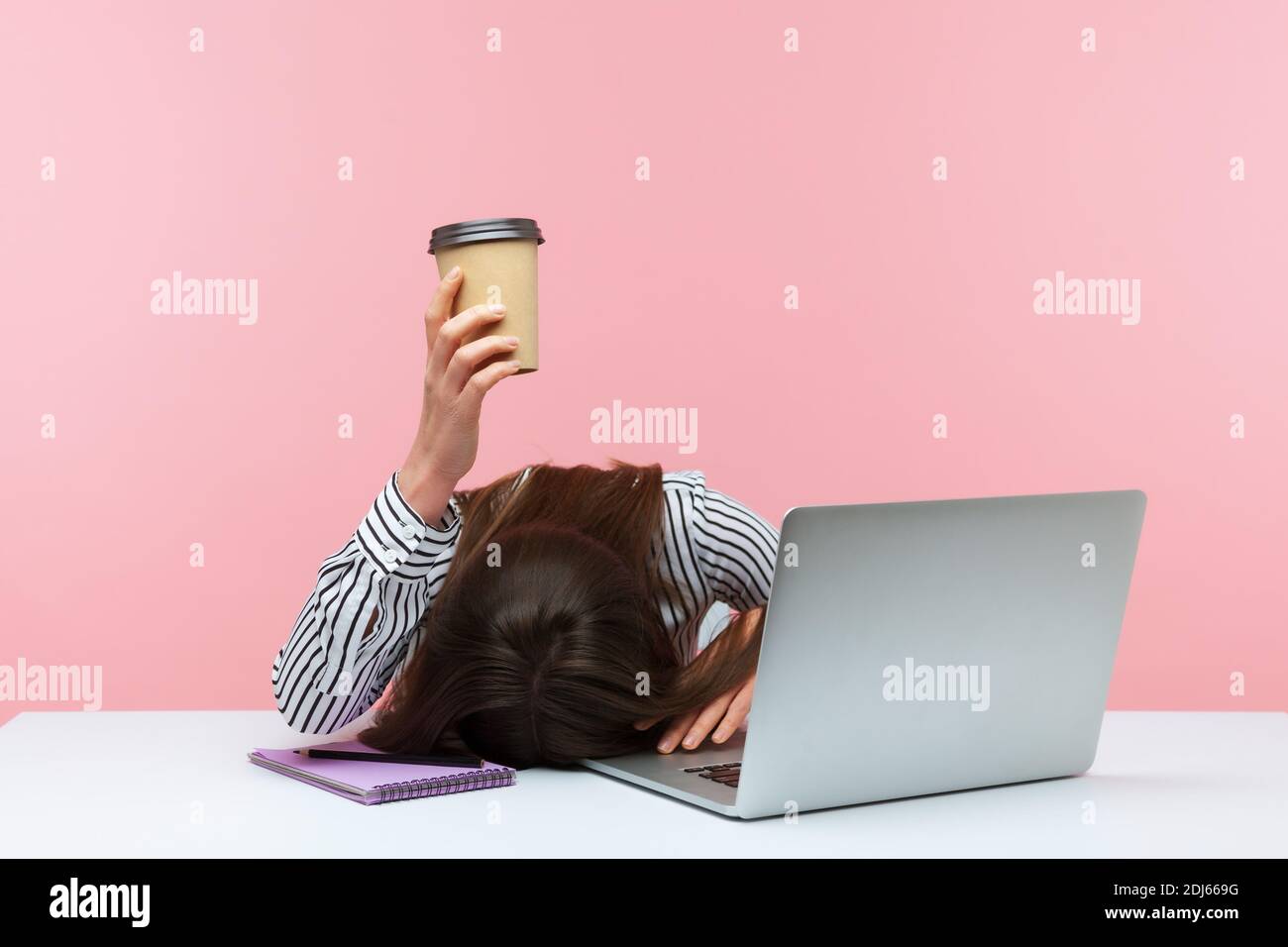 Verschlafene gelangweilte Büroangestellte, die auf dem Tisch lag, den Laptop hielt und die Papierkaffeetasse zeigte, und am Arbeitsplatz das Gefühl hatte, dass es an Energie mangelte. Innen Stockfoto