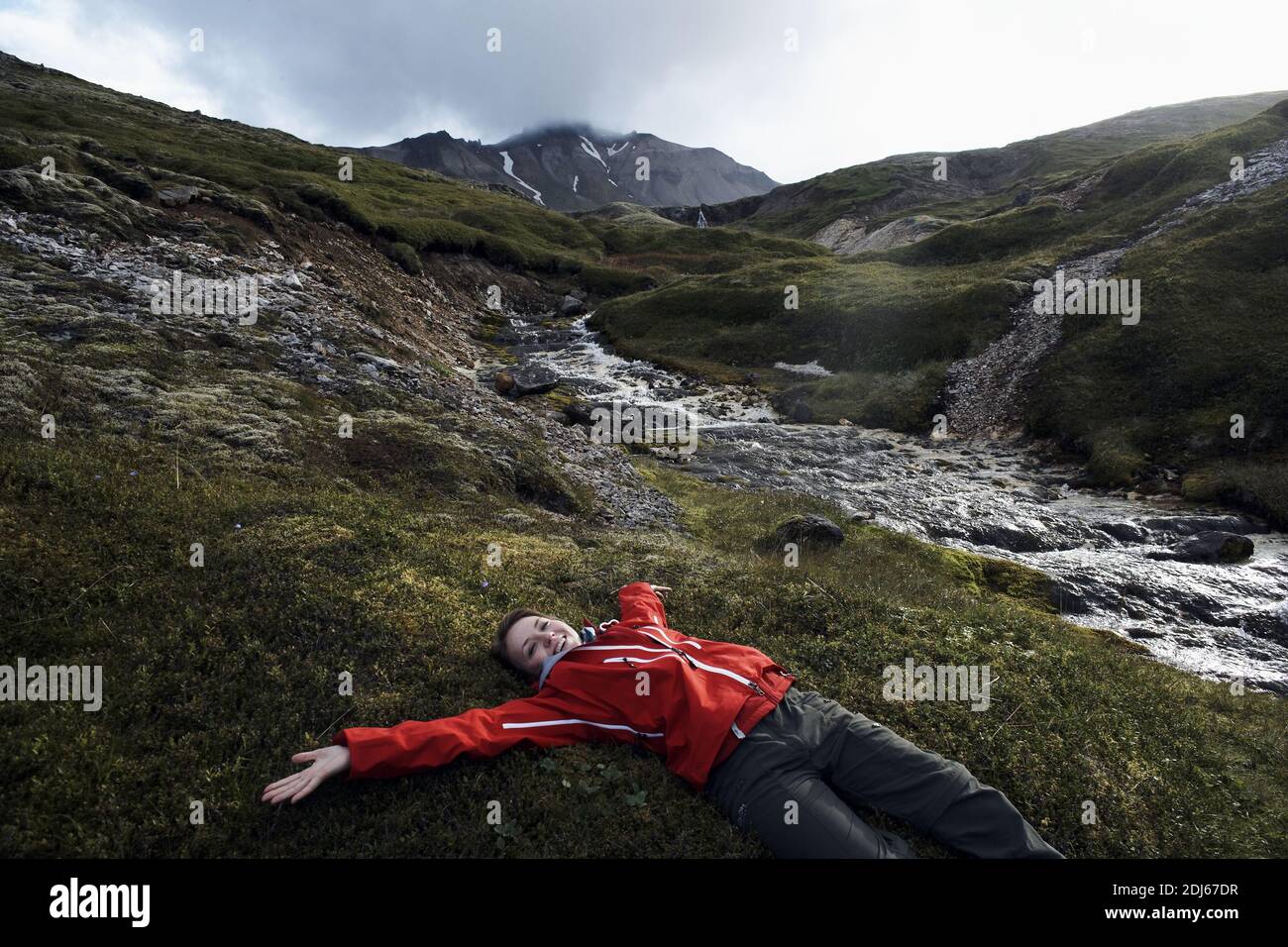 Entspannende Frau, die auf Gras liegt, in Ostisland, Island Stockfoto