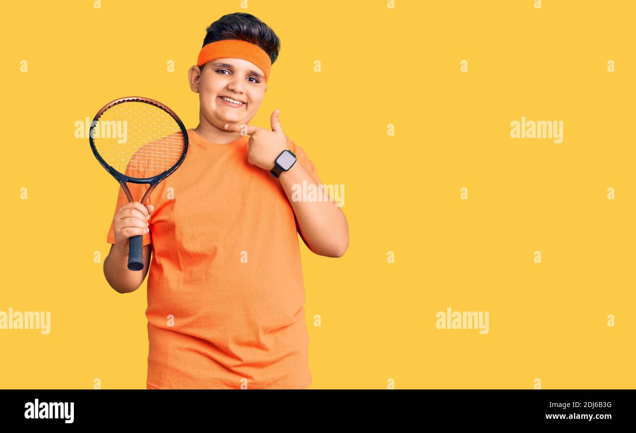 Kleiner Junge Kind spielt Tennis halten Schläger lächelnd glücklich zeigt  Mit Hand und Finger Stockfotografie - Alamy