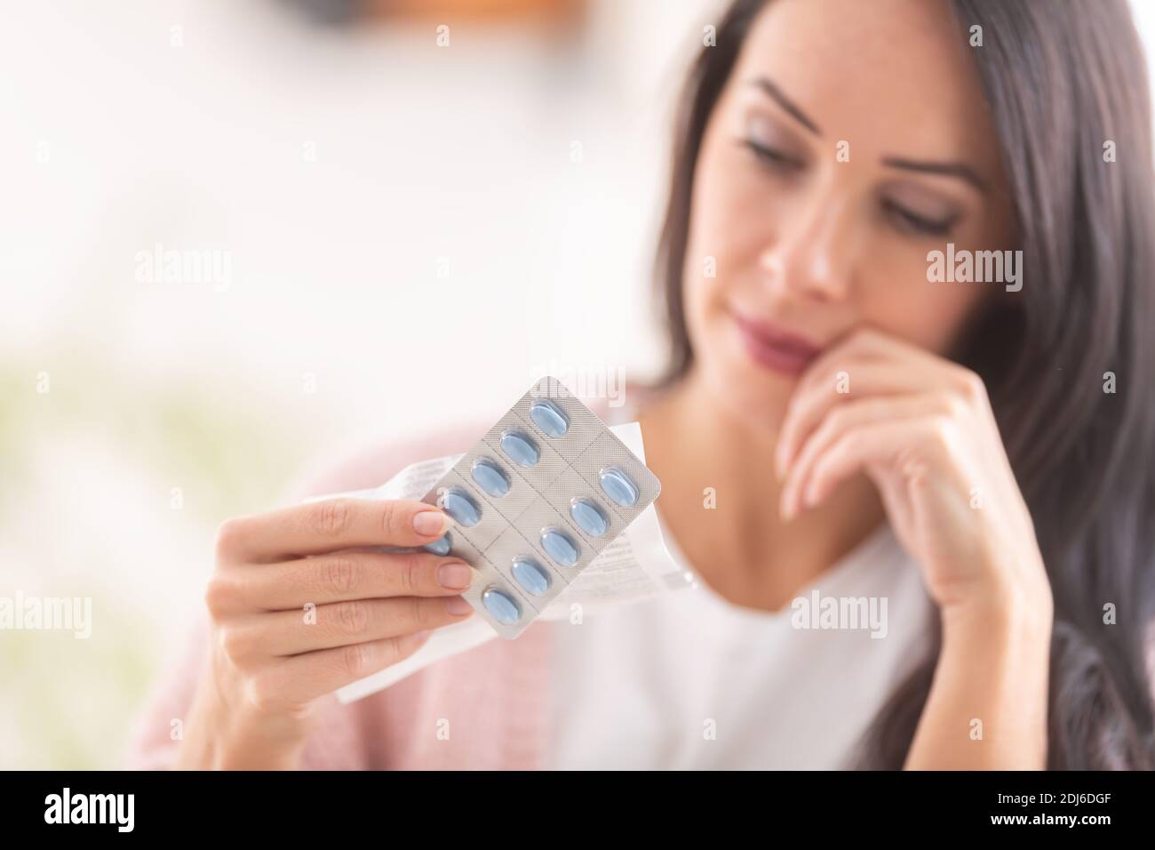 Frau erwägt die Einnahme einer Pille Blick auf die Blisterpackung. Stockfoto