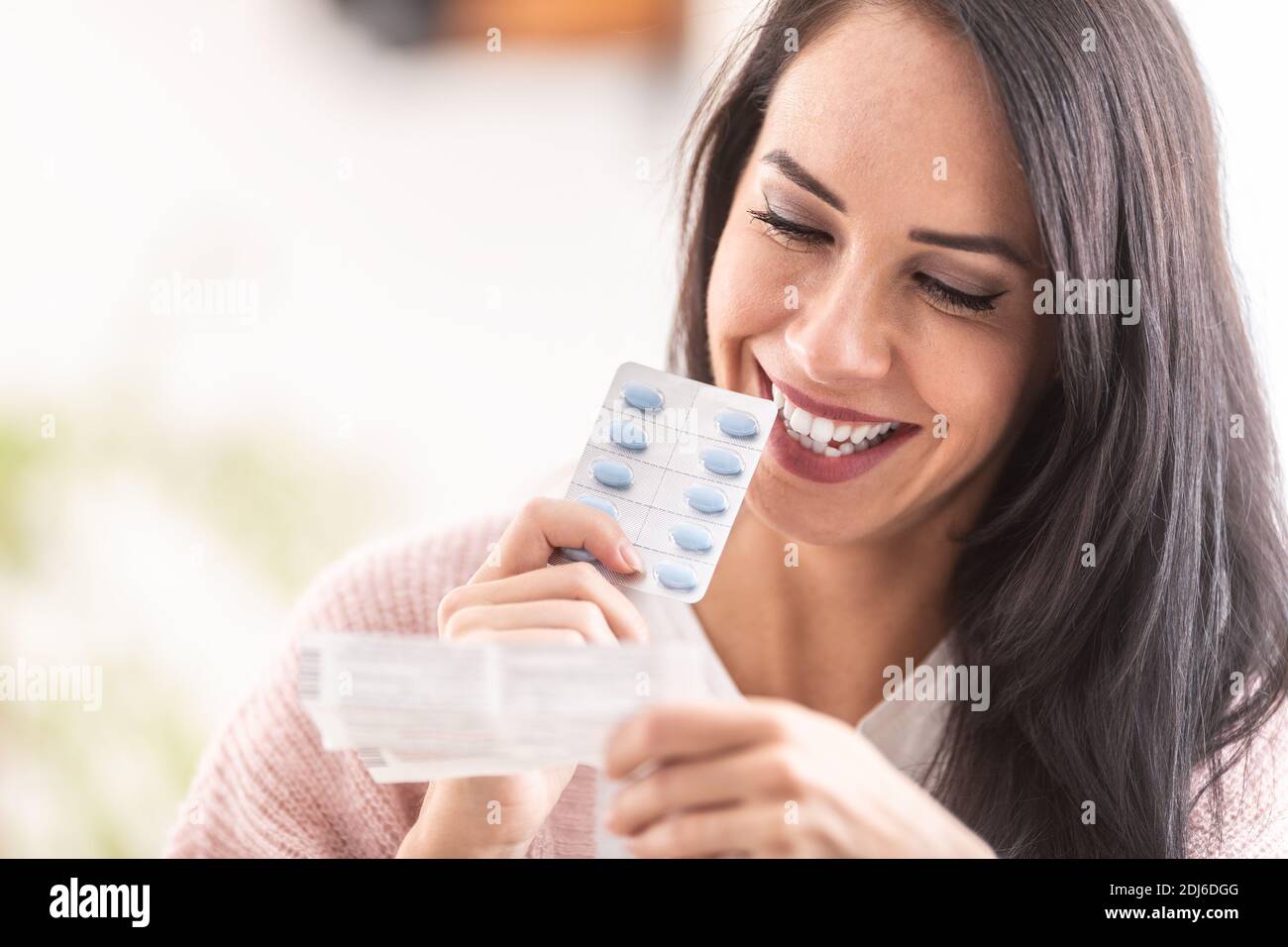 Frau liest ein Etikett der Pillen Verpackung, lächelnd. Stockfoto