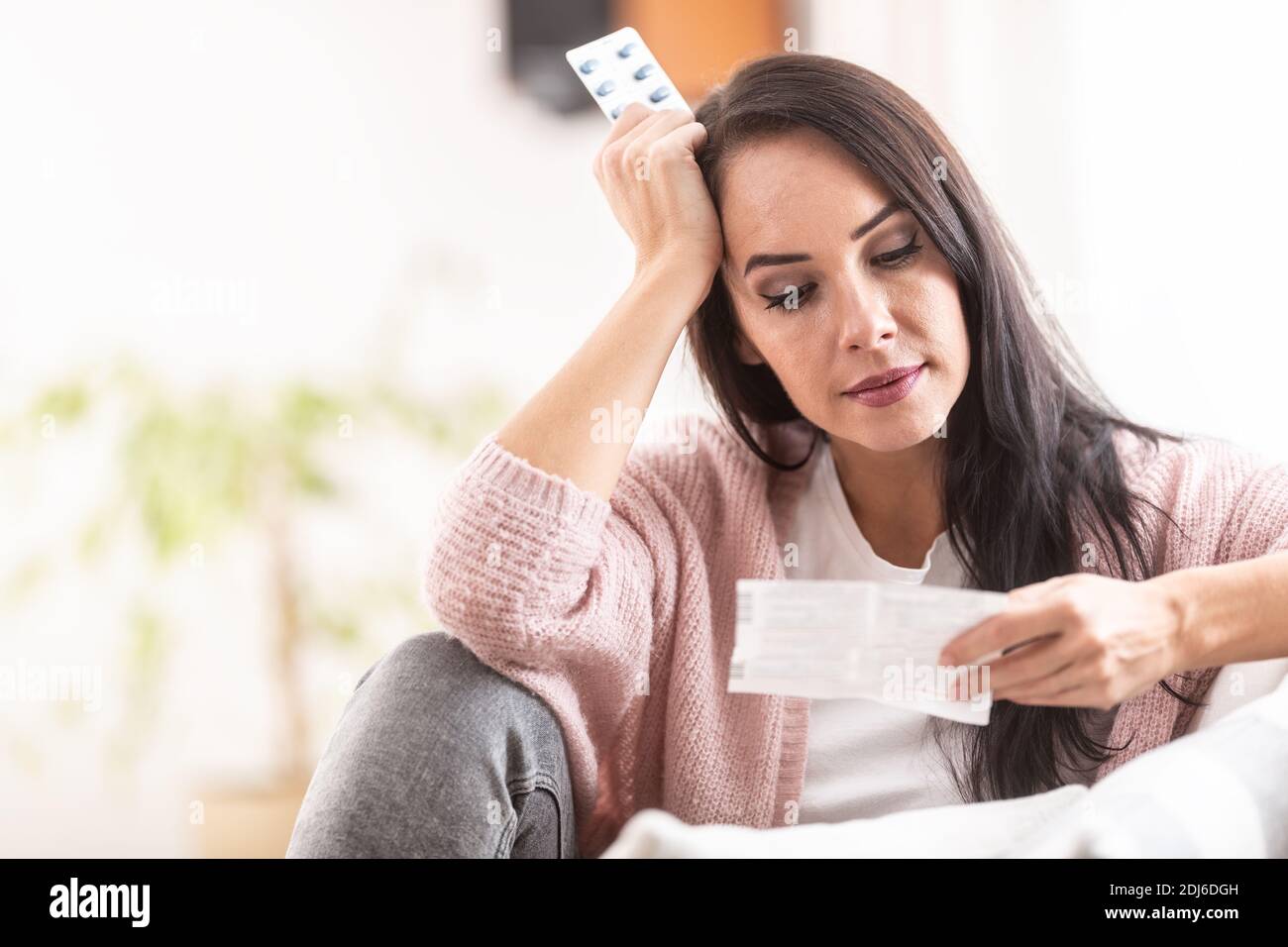 Besorgter Ausdruck auf dem Gesicht einer Frau, die ein Etikett der Medikamentenverpackung liest. Stockfoto