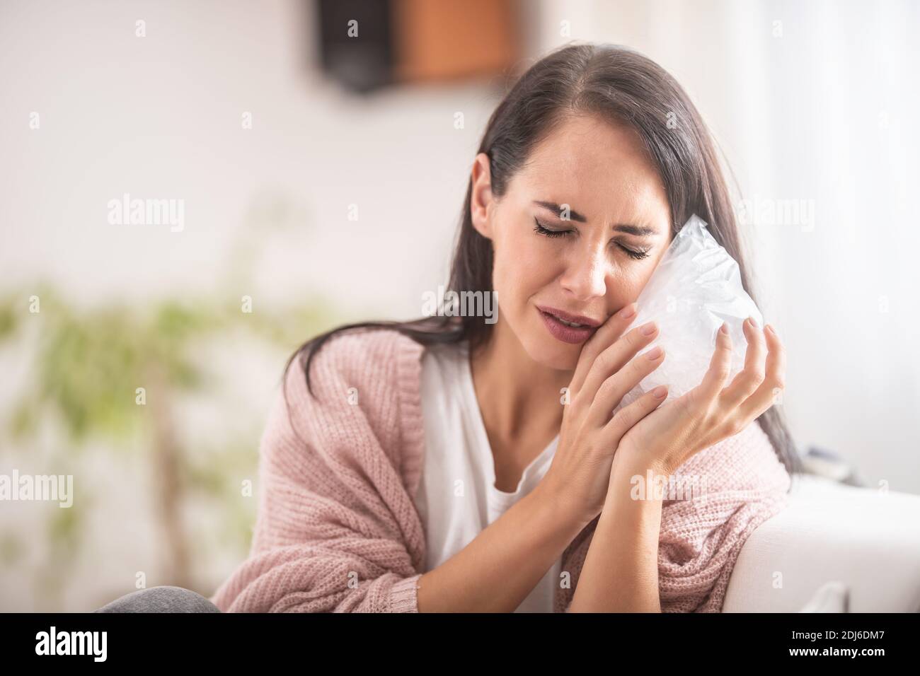 Eine Anstrengung eines Mädchens, schmerzende Zähne durch einen Beutel Eis zu Hause zu erleichtern. Stockfoto