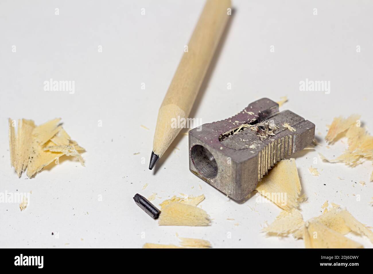 Gebrochener Bleistift mit Metallspitzer, gebrochene Bleistange und Späne auf weißem Papier Hintergrund Stockfoto