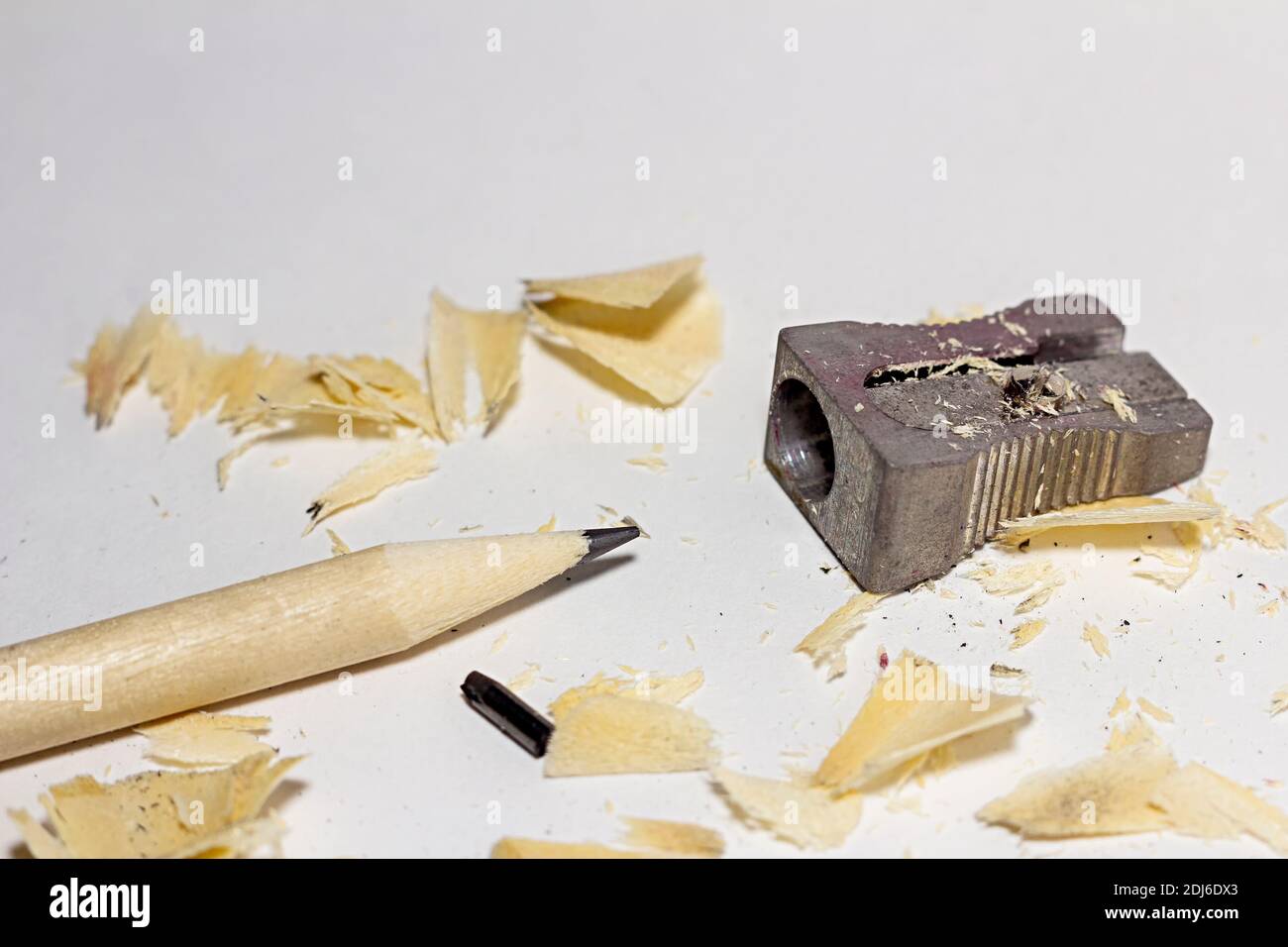 Gebrochener Bleistift mit Metallspitzer, gebrochene Bleistange und Späne auf weißem Papier Hintergrund Stockfoto