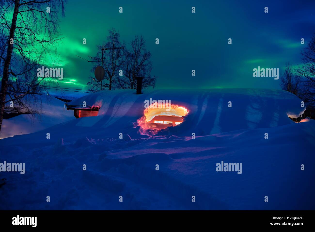 Berghütte vollständig unter Schnee begraben, Nachtfoto mit grünen Aurora Lichter hinter schweren Winterwolken. Nordschweden, Lappland, Joesjo Dorf. Gewinnen Stockfoto